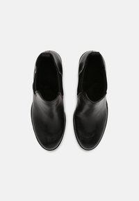 Black leather ankle boots with a smooth finish, elastic side panels, rounded toes, and a low, flat sole. No visible hardware or patterns.