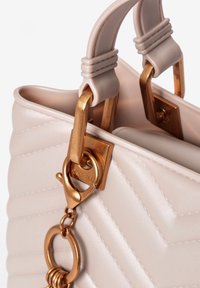 Weiche rosa gesteppte Handtasche mit goldfarbenen Beschlägen, die ein strukturiertes Design, doppelte Griffe und ein dekoratives Kettendetail bietet.