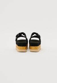 Sorte plattform sandaler med en espadrille-stil vevd jute-base, justerbare spenne-stropper og en teksturert gummisåle.
