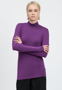 Langarm-Turtleneck-Shirt in lila, aus weichem Stoff. Bietet einen taillierten Schnitt mit glatter Textur und dezentem Logodetail am Saum.