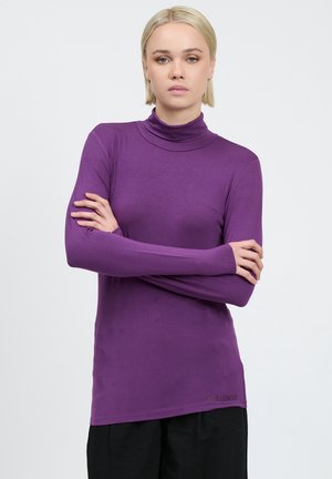 Long-sleeve turtleneck shirt in purple, made of soft fabric. Features fitted design with a smooth texture and subtle logo detail at the hem.