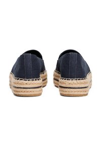 Tengerészkék vászon espadrille-ek juta kötésű talppal. Lapos dizájn jellemzi, rugalmas nyílásokkal, fekete varrással kiemelve.