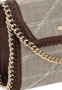 Beige tekstil skuldertaske med et vævet mønster, der har brune læderdetaljer og en sølvfarvet kædestrop. Inkluderer synlige syninger.