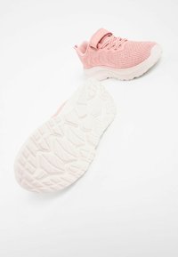 Rosa Sportschuhe mit einem strukturierten Strickobermaterial, verstellbarem Riemen und einer weißen Gummisohle mit einem gemusterten Profil für besseren Halt.