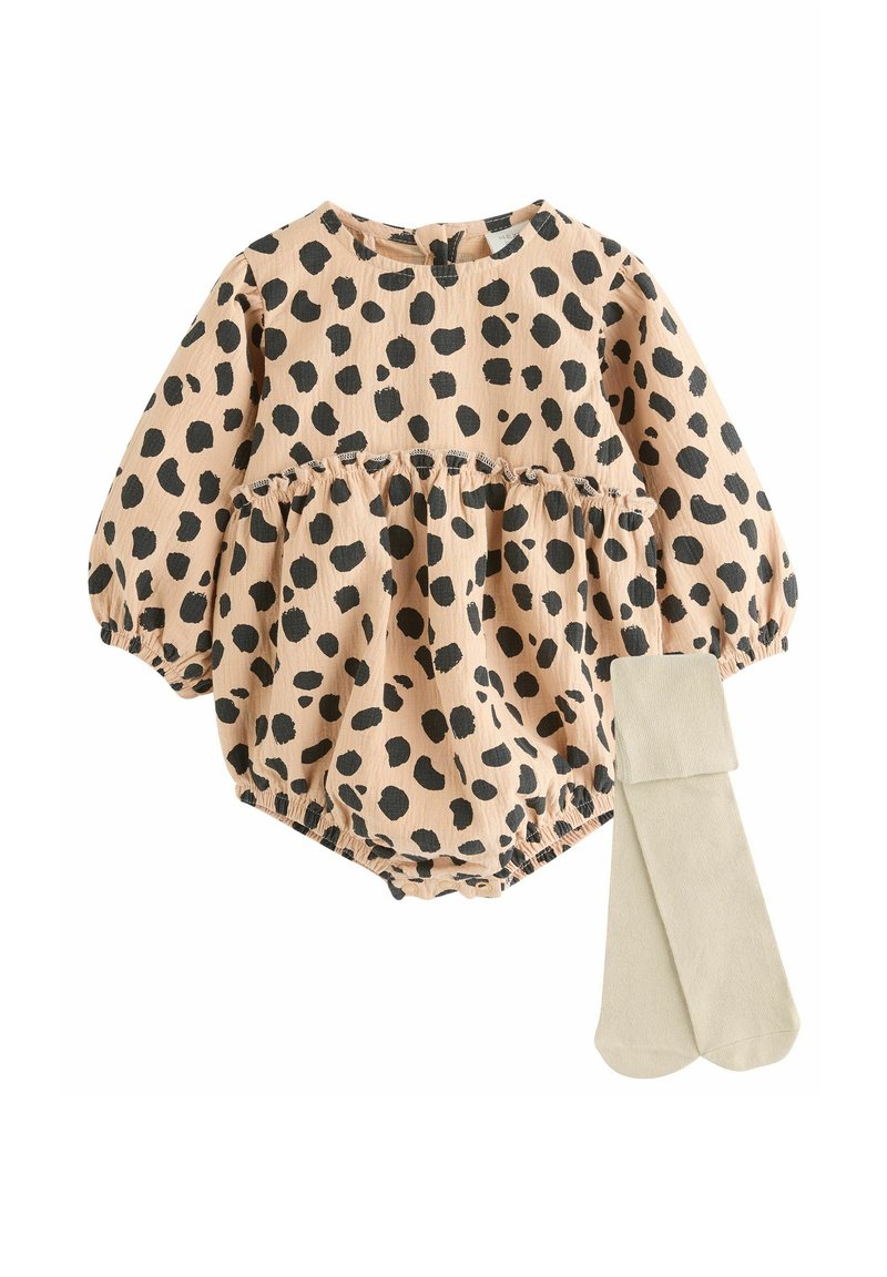 Bomullsoverall i persika med svarta leopardfläckar, med puffärmar och resår i midjan, tillsammans med beige strumpbyxor.