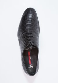 Chaussure noire à lacets présentant une tige en cuir texturé avec un motif en grille, un bout arrondi et une doublure intérieure lisse.