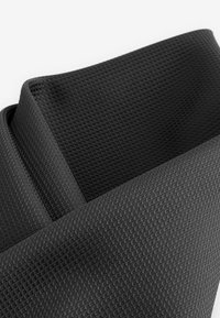 Sort tekstureret stof med et diamantmønster. Materialet ser let og fleksibelt ud, med bløde kanter og en glat overflade.