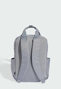 Gray backpack made from textured fabric, featuring padded shoulder straps, top handle, and side pockets for additional storage.