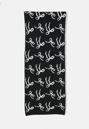 Écharpe noire avec un motif de ciseaux blancs répétés, fabriquée dans un tissu doux avec une finition texturée. Forme rectangulaire, adaptée à divers styles.