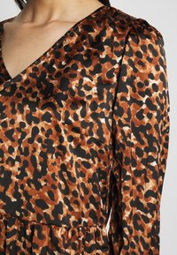 Leopardmönstrad klänning med V-ringning, i nyanser av brunt och svart, gjord av ett smidigt tyg med en lätt lyster och resårmidja.