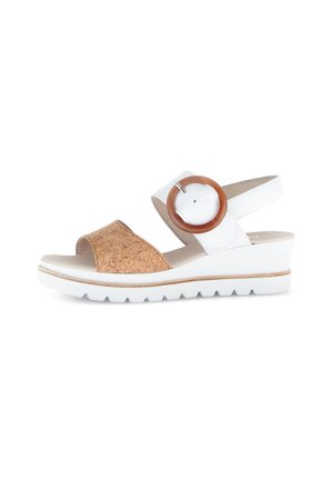 Cork and white leather sandal with a block heel. Features a wide strap and a large circular brown accent on the adjustable ankle strap.