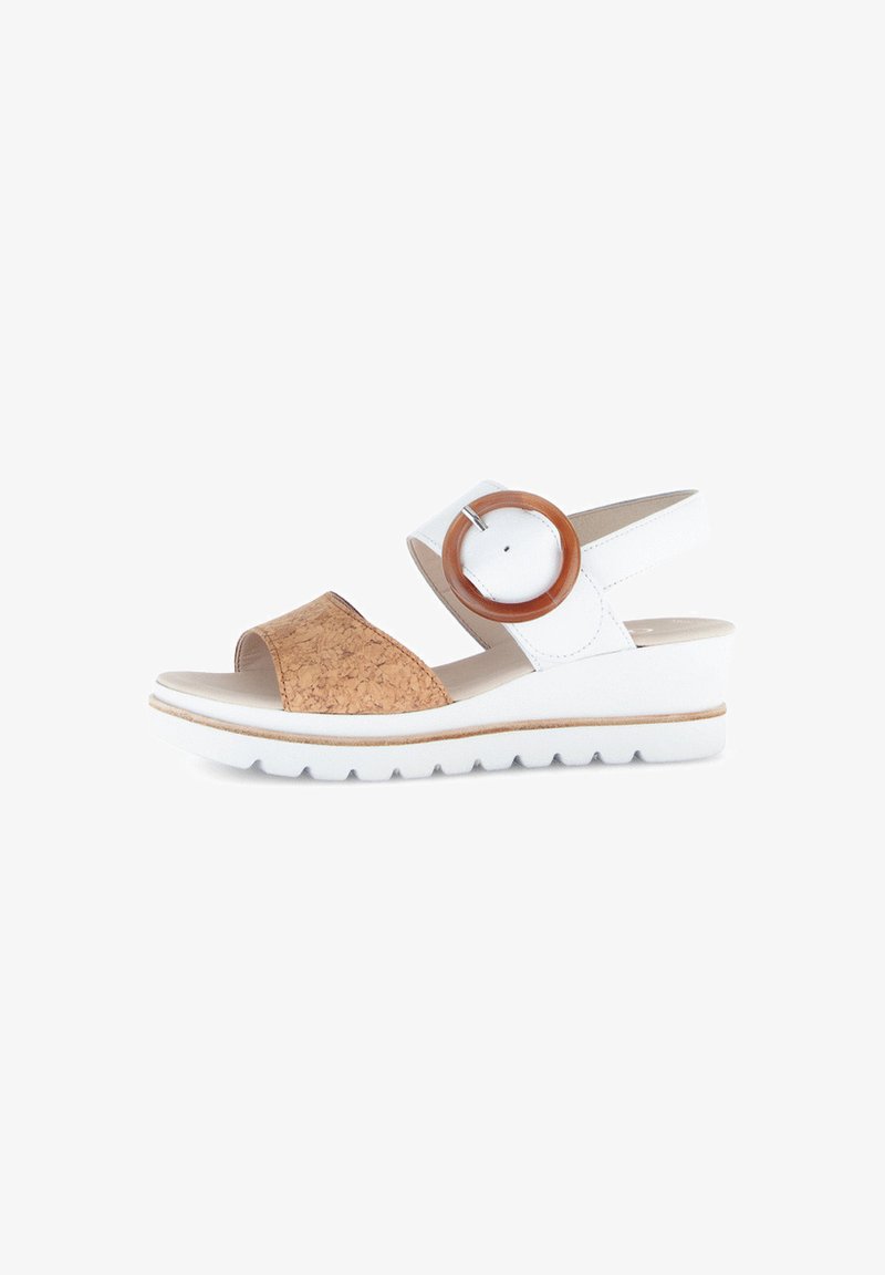 Cork and white leather sandal with a block heel. Features a wide strap and a large circular brown accent on the adjustable ankle strap.