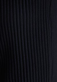 Tejido de ribetes negros con líneas verticales, suave al tacto y con un brillo sutil, adecuado para diversas aplicaciones de ropa.