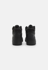 Zapatillas altas negras de piel suave con forro de tela negra aterciopelada en el cuello. Suela de goma plana con patrón de agarre texturizado.
