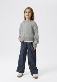 Pull à capuche gris en tricot avec un design court, associé à un pantalon large rayé bleu marine et des baskets blanches avec des accents beiges.
