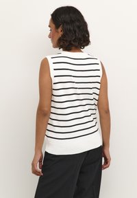 Débardeur en tricot blanc sans manches avec des rayures horizontales noires. Il présente un col rond et un design ajusté, se terminant au niveau des hanches avec un ourlet côtelé.