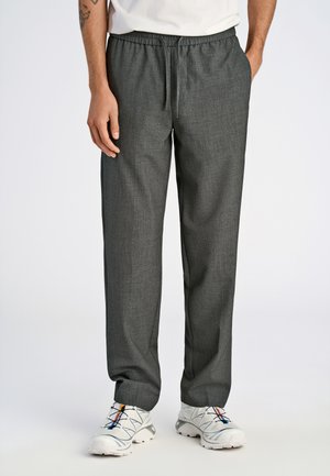 Graue, texturierte, elastische Bundhose mit einem lockeren Schnitt, kombiniert mit weißen Sportschuhen, die farbenfrohe Akzente und ein strukturiertes Design aufweisen.