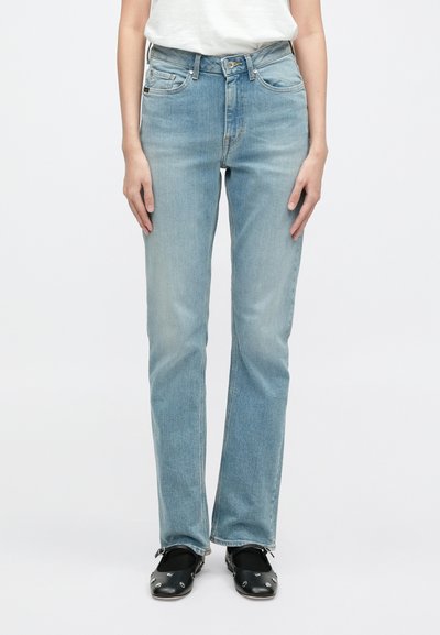 Jeans de denim azul claro com corte reto, apresentando cinco bolsos, um efeito desbotado e um clássico fecho com botão e zip. Efeito.