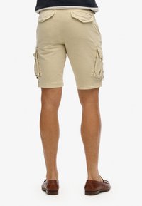 Bermudas de carga color caqui con dos bolsillos laterales, bolsillos traseros con solapa y un diseño a la altura de la rodilla. Hechas de una tela ligera con una textura suave.