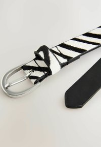 Ceinture à imprimé zèbre avec un design texturé noir et blanc, boucle en métal argenté et dos en cuir noir lisse.