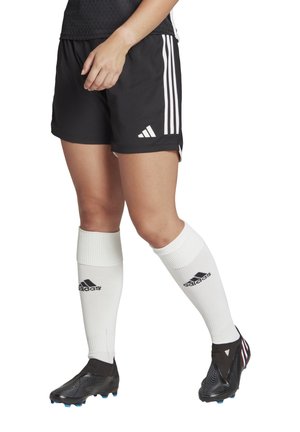 Black athletic shorts with three white stripes and logo, paired with knee-length white socks and black soccer cleats featuring a textured design.