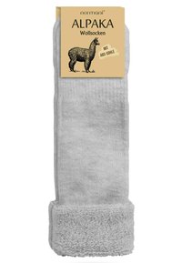 Helle graue Socken aus Alpaka-Wolle mit einem dicken, strukturierten Bündchen. Die Verpackung zeigt eine Illustration eines Alpakas sowie eine auffällige schwarze Schrift.