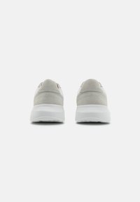 Zapatillas de ante y sintéticas con un upper gris claro, suela blanca, forma redondeada y diseño minimalista. Sin marcas ni acentos visibles.
