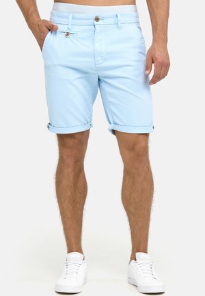 Shorts en coton bleu clair avec une fermeture à bouton, poches latérales, ourlets retroussés et une taille texturée, associés à des baskets blanches.