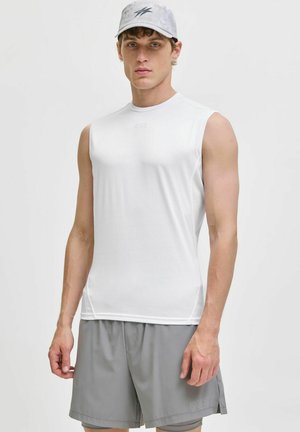 Weißes ärmelloses Sportshirt mit glatter Textur und einem seitlichen Netzpaneel, kombiniert mit grauen Shorts, die ein Logo tragen.