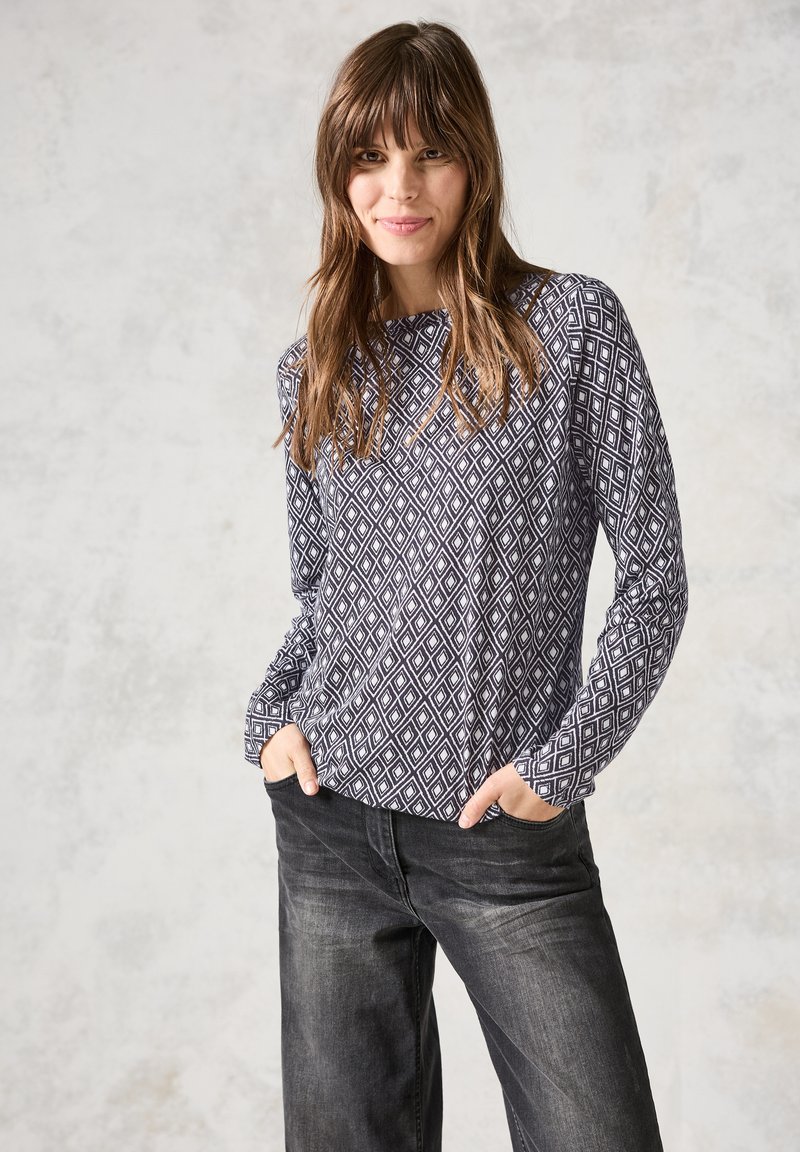 Haut à manches longues avec un motif en losanges bleu marine et blanc, tissu doux, col rond, coupe décontractée ; associé à un jean sombre et ample.