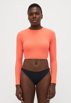 Long-sleeve cropped top in textured coral fabric, paired with black bikini bottoms. Features a round neckline and ribbed detailing.