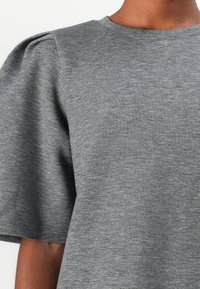 Maglia grigia a maniche corte realizzata in morbido tessuto testurizzato. Presenta spalle a palloncino e un collo rotondo per un fit rilassato.