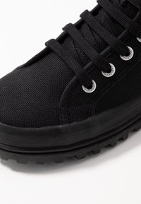 Czarne sneakersy za kostkę wykonane z teksturowanej kanwy. Posiadają okrągłe metalowe oczka, czarne sznurowadła oraz wytrzymałą gumową podeszwę.