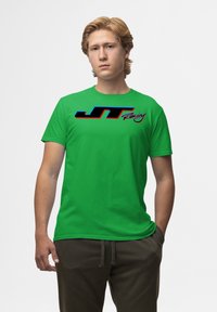 Zelené bavlněné tričko s černým a modrým logem "JT Racing". Krátké rukávy, kulatý výstřih a hladká, lehká textura.