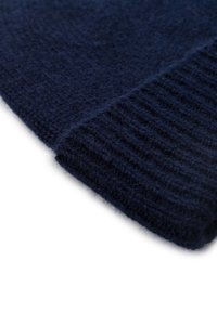 Tissu en laine tricoté bleu marine, présentant une texture côtelée sur le bord et une surface lisse. Gros plan mettant en avant sa douceur.