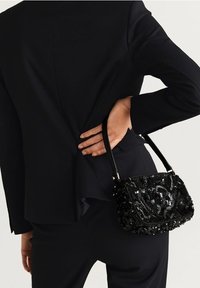 Borsa a tracolla nera in paillettes con forma rettangolare, dotata di una maniglia corta e dettagli intricati di perline. Indossata in vita.