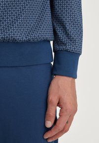Marineblauwe sweatshirt met een geometrisch wit patroon, voorzien van geribde manchetten en zoom. Glad textuur, losse pasvorm.