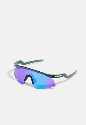 Óculos de sol com um design envolvente, lentes espelhadas em azul e roxo, armação verde e braços angulados distintos.