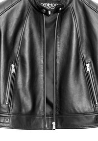 Giacca di pelle nera con colletto alto, dotata di cerniere in argento sul davanti e tasche, e pannelli testurizzati sulle spalle.
