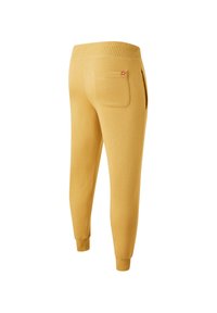 Yellow jogger pants made from soft fabric, featuring a ribbed waistband, elastic cuffs, and a single back pocket with an accent logo.