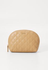 Bolsa cosmética acolchada en color beige, con forma redondeada, logotipo dorado en la parte superior y cierre con cremallera. Textura suave y brillante.