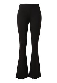 Zwarte flared leggings van rekbaar materiaal; hebben een gladde textuur, hoge tailleband en een subtiele logodetail nabij de heup.