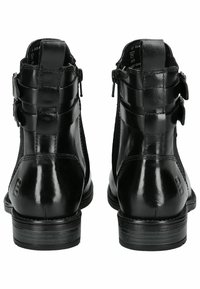 Botas de tobillo de cuero negro con un acabado liso, que cuentan con dos correas ajustables y una cremallera en la parte trasera. Punta redonda y tacón bajo apilado.