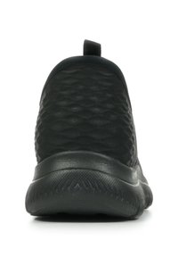 Zapatilla negra sin cordones con un upper texturizado, punta redondeada y suela flexible, que cuenta con una pestaña en la parte trasera para facilitar su uso.