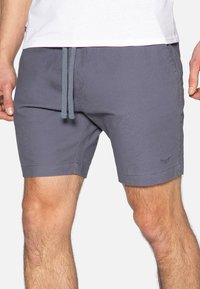 Pantaloni corti grigi realizzati in un tessuto morbido con vita elasticizzata e cordoncino. Presentano tasche laterali e un piccolo logo ricamato sulla gamba.