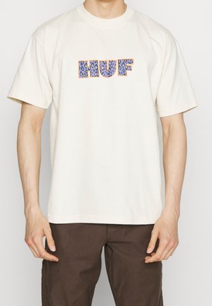 Bawełniany t-shirt w kolorze kremowym z grafiką logo "HUF" w fioletowo-niebieski wzór lamparta, krótkimi rękawami i luźnym krojem.