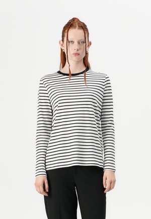 Langärmliges T-Shirt in Weiß mit schwarzen horizontalen Streifen, rundem Halsausschnitt und lässiger Passform. Getragen mit schwarzen Hosen.