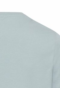 Jasnoniebieska koszulka z krótkim rękawem wykonana z miękkiej tkaniny. Ma okrągły dekolt i gładką fakturę bez widocznych wzorów czy akcentów.