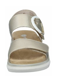 Light beige strap sandal with a textured finish, white accent buckle, and a cushioned sole. Features an open toe and adjustable straps.