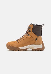 Bottes de randonnée marron avec une tige en cuir imperméable, un col de cheville texturé marron et une semelle en caoutchouc robuste. Présente un matériel de laçage en métal.